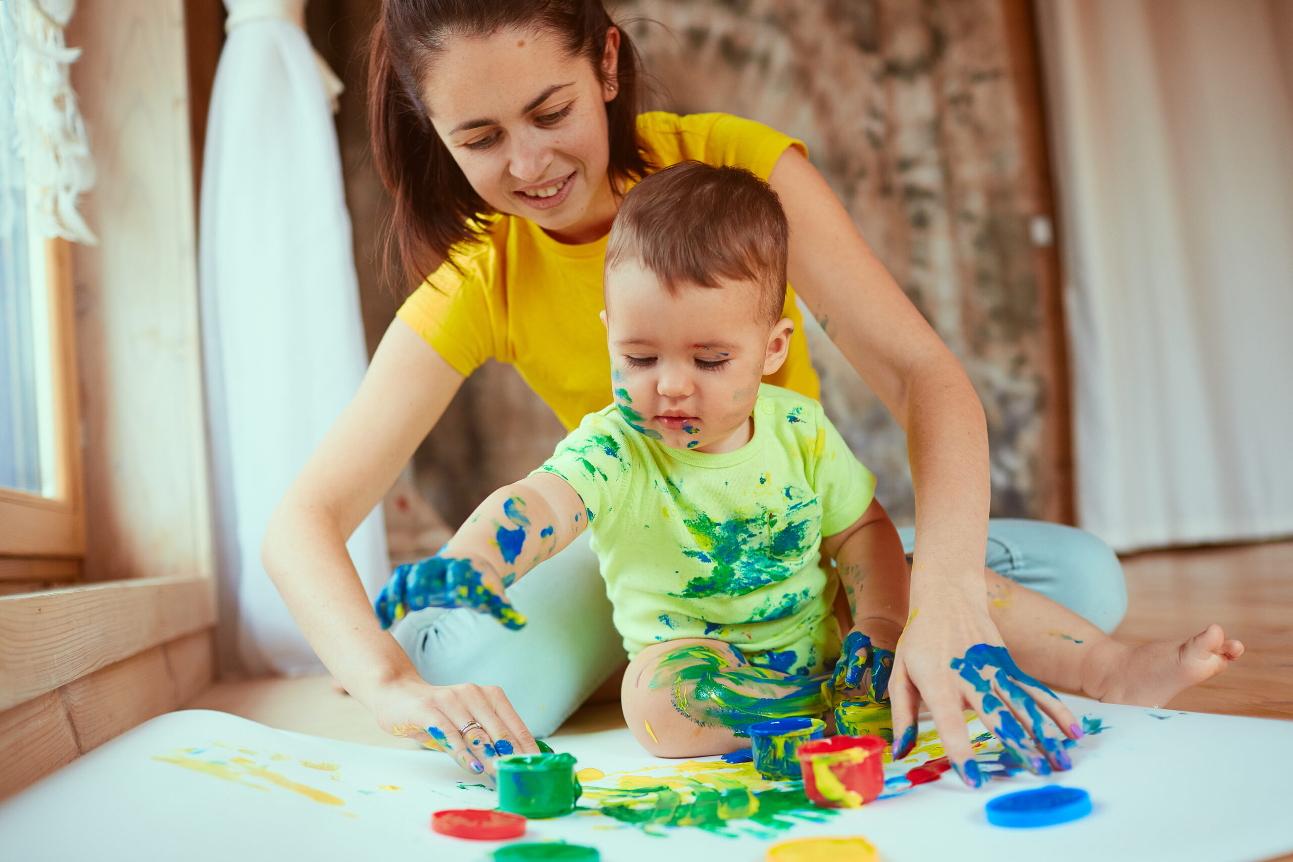 The mother with son painting a big paper by hands